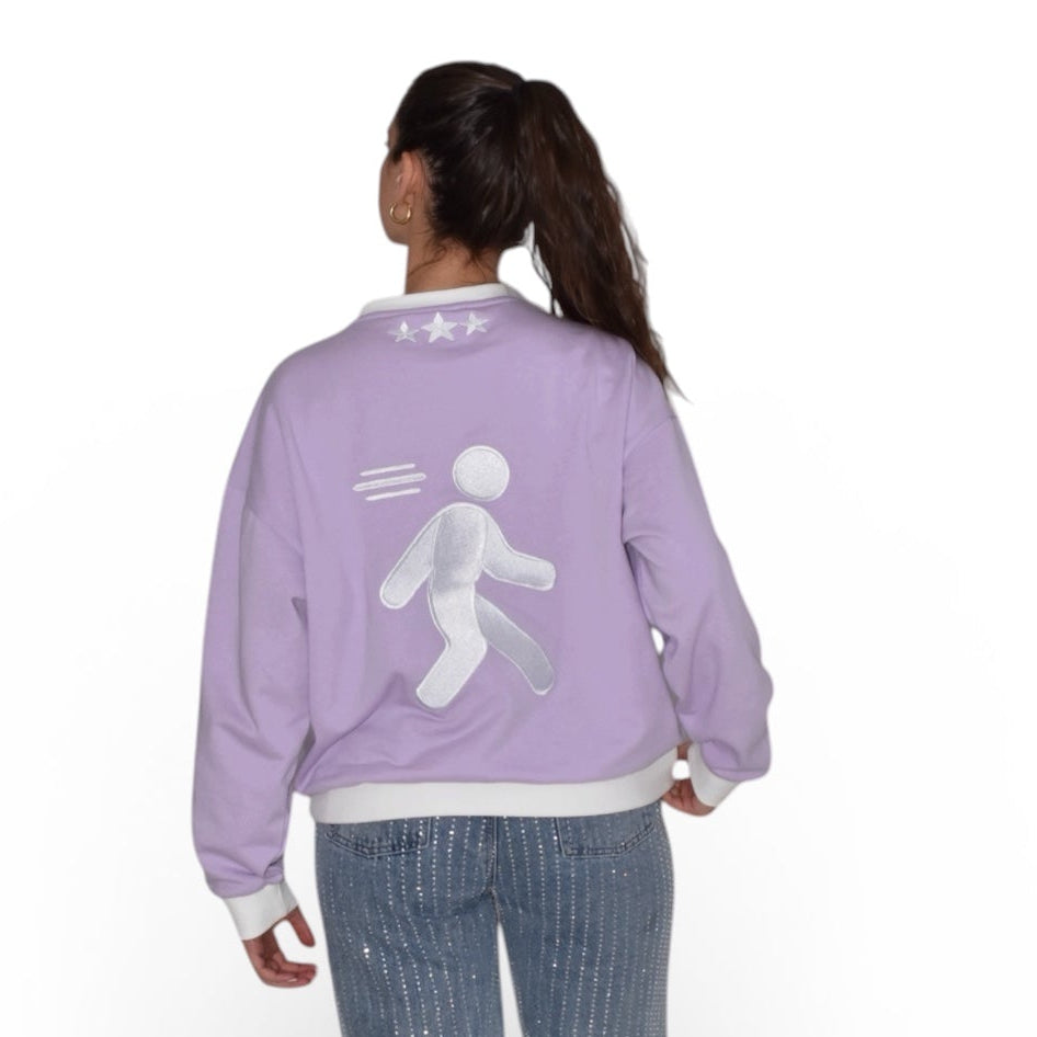 wearing a lilac crewneck with a white graphic on the back, standing against a white background